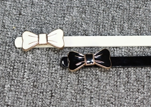 Détail de barrettes à cheveux nœud noir et blanc avec bordure dorée sur surface texturée