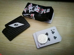 Mini playing cards set with black box next to a coin for size scale on wood table