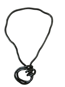 Detail of a flexible black metallic snake chain necklace tied in a complex knot on white background