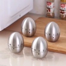 Close-up of egg-shaped mechanical kitchen timers in brushed stainless steel on wood