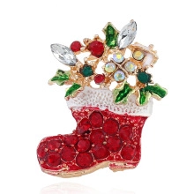 Dettaglio macro della spilla calza di Natale con cristalli rossi e foglie di agrifoglio