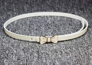 Gros plan sur une ceinture fine en cuir verni blanc avec boucle en métal doré en nœud