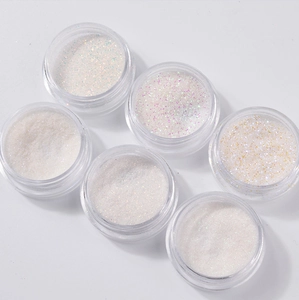 Six jars of white shimmering nail powder with iridescent green, purple, and gold glitters