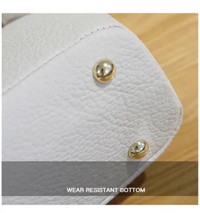 Detailopname van de witte litchi lederen tasbodem met gouden metalen beschermende noppen