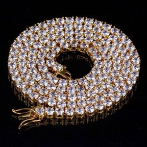 Detailed view of gold tennis chain with pavé zircon stones on a black background
