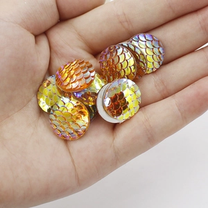 Macro shot of 16mm orange-gold resin flatback scales with sparkling fish scale texture