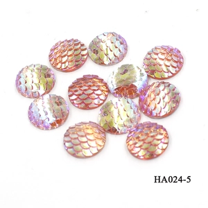 Macro shot of 16mm round resin fish scale cabochons with pink orange iridescent finish