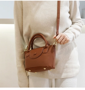 Detailopname van mini bucket bag van karamelkleurig leer met lycheekorrel en goud accent