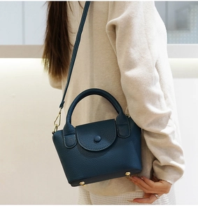 Detailweergave van marineblauwe mini-tas van leer met gouden metalen voetjes