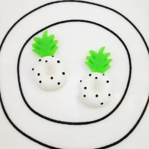 Close-up of two white resin pineapple charms with black dots for DIY craft projects
