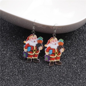 Detailed close-up of acrylic Santa Claus earrings with gift box on black glitter background
