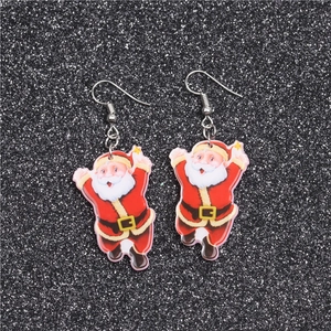 Close-up of Santa Claus acrylic earrings with sunglasses on black glitter background