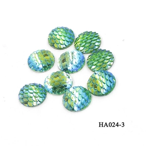 Macro detail of 16mm round iridescent fish scale resin cabochons with green blue gradient