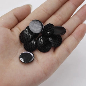 Macro shot of 16mm black resin mermaid scales for DIY jewelry and craft projects