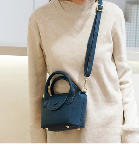 Detail van mini groenblauwe lederen crossbodytas met riem en gouden metalen studs