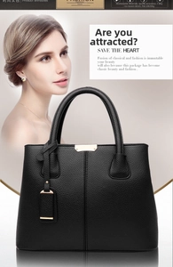 Detail of black lychee grain leather handbag with gold hardware and stylish top handle
