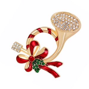Macro detail of a gold horn brooch with red bow, green holly leaves and crystals