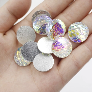 Close-up of 16mm holographic fish scale resin cabochons held in hand for DIY jewelry