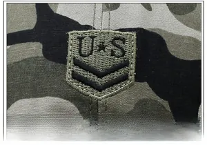 Détail macro du tissu camouflage avec écusson brodé militaire et surpiqûres de précision
