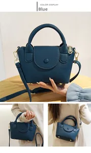 Detail van blauwe handtas van lycheeleer met gouden gespen en ronde handgrepen