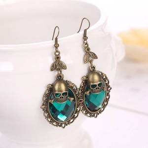 Detailed view of punk skull earrings featuring green gems and vintage bronze finish