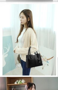 Detail of black litchi texture leather handbag featuring elegant gold-tone hardware