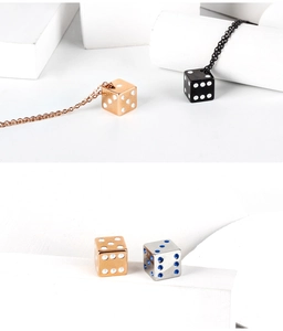 Detailed view of dice pendants in rose gold, black, and silver with metal finish