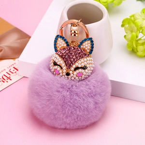 Gros plan du porte-clés renard en fourrure violette avec détails en métal or rose