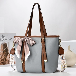 Detail of grey pebble leather bucket bag with brown handles and bohemian wide strap