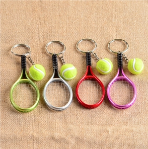 Detailed shot of tennis racket keychains in four colors on a rustic burlap surface