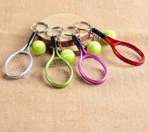 Detailed view of colorful tennis racket and ball keychains on rustic wood and linen