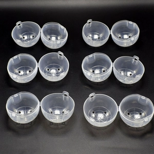 Detail of 6 clear plastic hinged capsules shown open with ventilation holes for vending