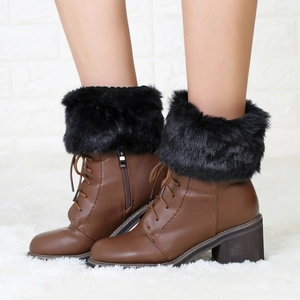 Detail of brown leather ankle boots with black faux fur trim and side zipper closure