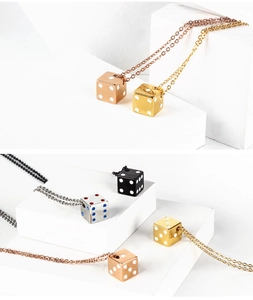 Detailed view of dice pendants in rose gold, gold, silver, and black on a white platform