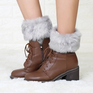 Close-up of brown faux leather ankle boots with grey faux fur collar and lace-up detail
