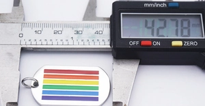 Digital caliper measuring the width of a rainbow enamel rectangular pendant, 14.27mm wide