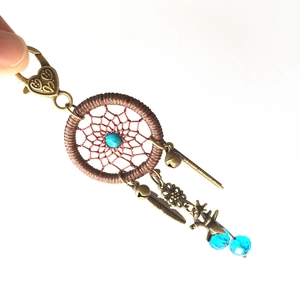 Detailed view of handmade dreamcatcher keychain with bronze feathers and blue beads