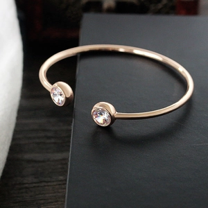 Close-up of rose gold open cuff bracelet featuring two round sparkling zircon accents