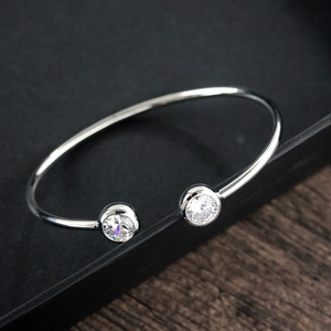 Detail of silver open bangle featuring two round clear cubic zirconia stones in macro view