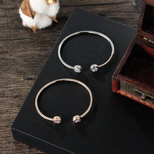 Close-up of silver and rose gold zircon bracelets on a black display stand