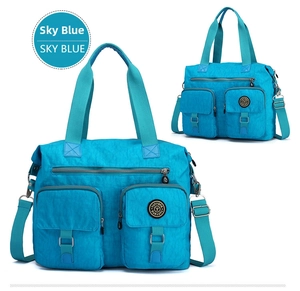 Detail view of sky blue waterproof nylon travel bag with multiple front utility pockets