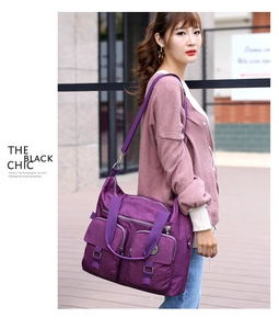 Detail of purple multi-pocket waterproof nylon shoulder bag on female model