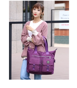 Detail of purple nylon handbag with dual front pockets and durable woven top handles