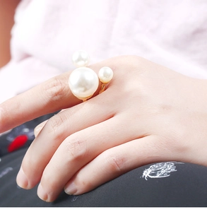 Detail of Mickey-shaped white pearl ring in gold finish worn on finger by a model