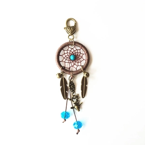 Detailed view of handmade dreamcatcher charm with metal feathers, blue beads, and deer pendant