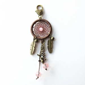 Detail of handmade dreamcatcher keychain with pink beads, bronze feathers and deer charm