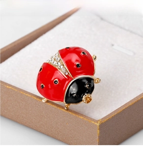 Macro detail of ladybug brooch with red enamel and sparkling rhinestones on gold metal