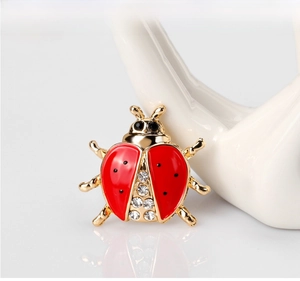 Detailed view of red ladybug brooch with crystals on a white ceramic hand base