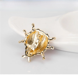 Detail view of the golden metal safety pin clasp and textured back of ladybug brooch