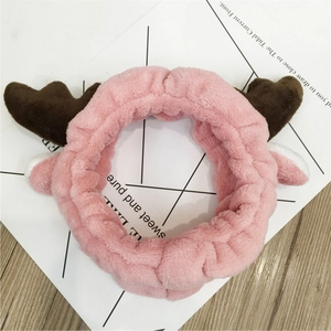 Close-up of pink plush reindeer antler headband with soft fabric ears on white card
